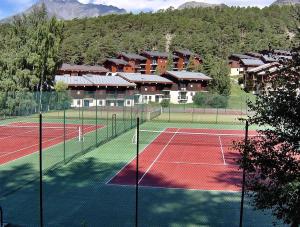 ラ・ノルマにあるappartement tous confort montagneの建物を背景にしたテニスコート