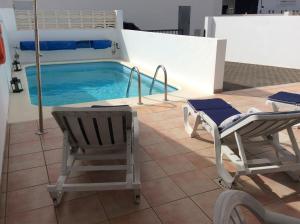 プラヤ・ブランカにあるVilla Anclazul Marina Rubiconのスイミングプール(椅子2脚、ベッド1台付)