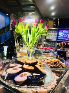 une exposition de biscuits et de pâtisseries sur un comptoir avec des fleurs roses dans l'établissement Camera & Caffè Cenni, à Fosso Ghiaia