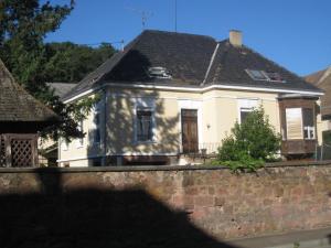 a white house behind a brick wall at Appartement et gîte Chez l'Habitant in Guebwiller