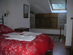 Un dormitorio con una cama roja y una ventana. en Alojamientos Rurales Navahondona, en Arroyo Frío 27 fotos más