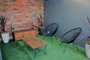 a bench and two chairs sitting next to a brick wall at Apartment 5ive in Devonport