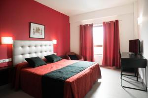 Dormitorio rojo con cama y TV en Hotel Cim Valles, en Santa Perpetua de Moguda