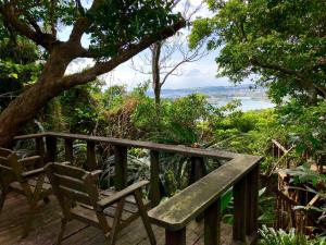 a wooden bench sitting on a deck with a tree at Kaiza in Nanjo
