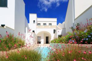 a white house with a courtyard with flowers at Palazzo Casto Relais in Taviano