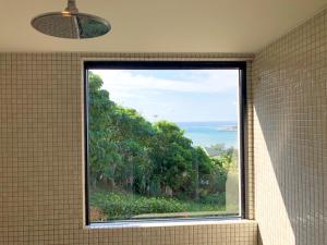 a window in a bathroom with a view of the ocean at Kaiza in Nanjo
