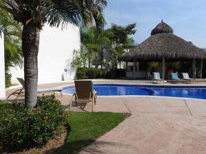 a resort with a swimming pool with a straw umbrella and chairs at Nuevo Vallarta Casa Neptuno in Nuevo Vallarta