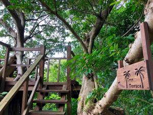 a tree house with a sign hanging from a tree at Kaiza in Nanjo