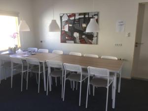 a dining room table with white chairs around it at Giljanes Hostel in Sandavágur