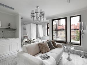 a white living room with a couch and windows at Sweet Suite in Gdańsk