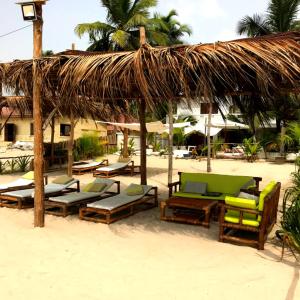 a group of lounge chairs and umbrellas on a beach at La Maison Blanche in Assinie