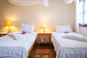 2 camas en una habitación con sábanas blancas y flores rosas en Kalkan Turk Evi, en Kalkan