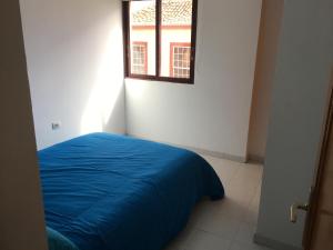 Un dormitorio con una cama azul y una ventana en Minipiso, en Los Llanos de Aridane