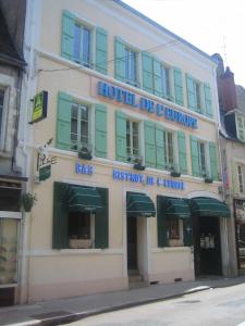ein Gebäude mit grünen Rollläden und ein Hotel de t Boutique in der Unterkunft Logis de L'Europe Restaurant Le Cepage in Corbigny