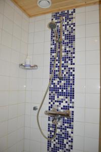 a bathroom with a shower with blue tiles on the wall at Pointin Vale Apartment Tahko in Tahkovuori
