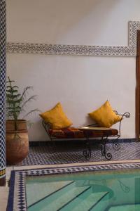 a couch with yellow pillows sitting next to a pool at Riad Jamaï in Fez