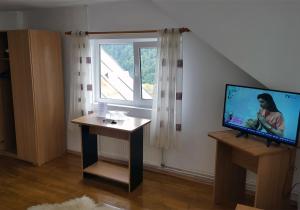 sala de estar con TV, mesa y ventana en Pensiunea Vila Gabriel en Sinaia