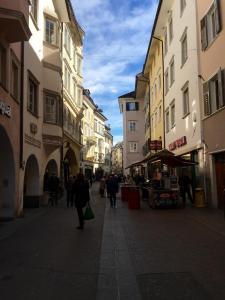 een groep mensen die door een straat met gebouwen lopen bij Iceman Room's Central in Bolzano