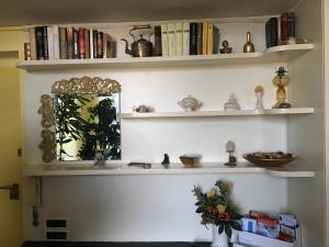 a room with shelves with books and a vase of flowers at Finestra su Genova - free parking in Genoa