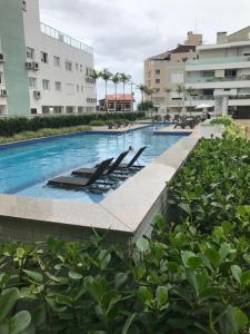 una piscina con tumbonas y edificios en Apartamento de 3 Quartos na Praia dos Ingleses, en Florianópolis