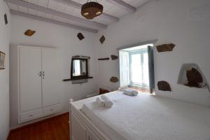 een witte kamer met een bed en een raam bij Patmos Chora traditional villa Genadio in Patmos