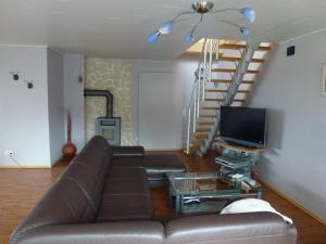 a living room with a brown couch and a television at Moderne Maisonette-Wohnung am Karpfenteich; modern Apartment with view of the carp pond in Barmstedt