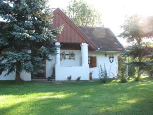 a white house with a brown roof and a yard at Berkenye Fogadó in Szalafő
