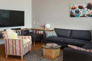 a living room with a couch and chairs and a flat screen tv at Kite View in Noordwijk aan Zee