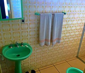 y baño con lavabo verde y toallas blancas. en Hotel Comodoro de Rosário Do Sul, en Rosário do Sul