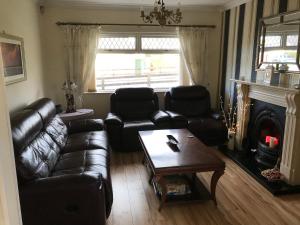a living room with leather furniture and a fireplace at Marcellas cottage in Omagh