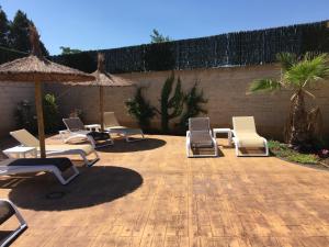 a group of lounge chairs and umbrellas on a patio at Cuatro Caminos in Piedrabuena