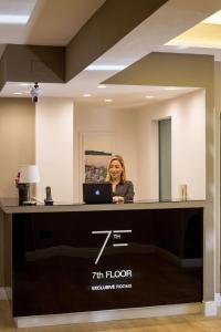 a woman sitting at a reception desk with a laptop at 7th Floor Suite in Naples