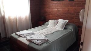 a bedroom with a bed with towels and a brick wall at Dos Soles in Mina Clavero