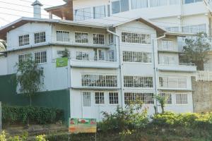 a white building with a green flag in front of it at Tea Hills Bungalow in Hatton