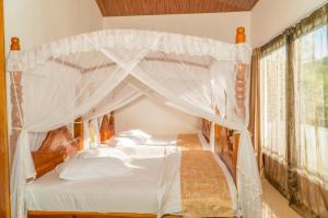 a bedroom with a canopy bed with white sheets and pillows at Tea Hills Bungalow in Hatton