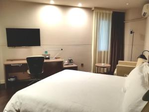a hotel room with a bed and a flat screen tv at Jinjiang Inn –The Mixc Subway, Nanning in Nanning