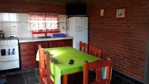 a kitchen with a green table and a white refrigerator at Dos Soles in Mina Clavero