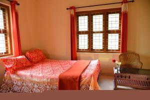 a bedroom with a bed and two windows at Nandanam Villa in Kaniyāmbetta
