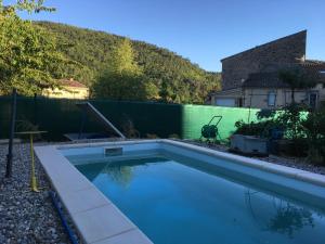 a swimming pool in a backyard with a green fence at Gîte de l’Eyrieux in Les Ollières-sur-Eyrieux