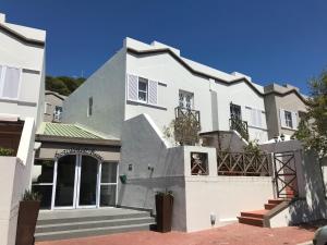 une grande maison blanche avec des escaliers en face de celle-ci dans l'établissement De Waterkant Piazza Apartments, au Cap
