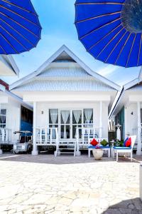 a white house with a blue umbrella and chairs at Balatoa in Bira