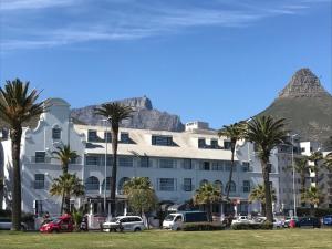 un grande edificio bianco con una montagna sullo sfondo di Green Point Self Catering Studios a Città del Capo