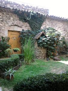 un edificio de piedra con una puerta de madera y plantas en La Maison d'hôtes, en Le Poujol-sur-Orb