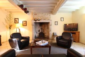 sala de estar con 2 sillas de cuero y chimenea en Gites Du Manoir de Savigny en Valognes