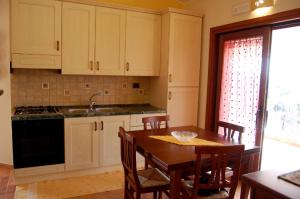 cocina con mesa de madera con sillas y fregadero en villa pascoli, en Domus de Maria