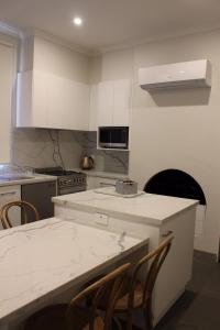 a kitchen with white cabinets and a table and chairs at Abbey View in Bendigo