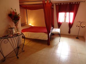 1 dormitorio con 1 cama con cortinas rojas y mesa en La Maison d'hôtes, en Le Poujol-sur-Orb