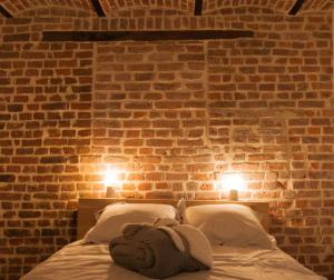 リエージュにあるLaGrange-Chambres d'hôtesのレンガの壁のベッドルーム1室、ベッド1台(2つの照明付)