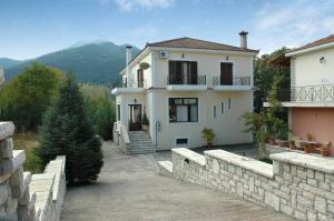 a large white house with a stone wall at Aroanios Hotel in Klitoria