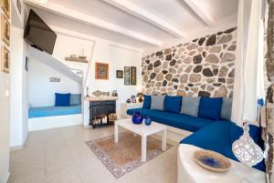 un soggiorno con divano blu e parete in pietra di Moschatos Beach House a Kamari